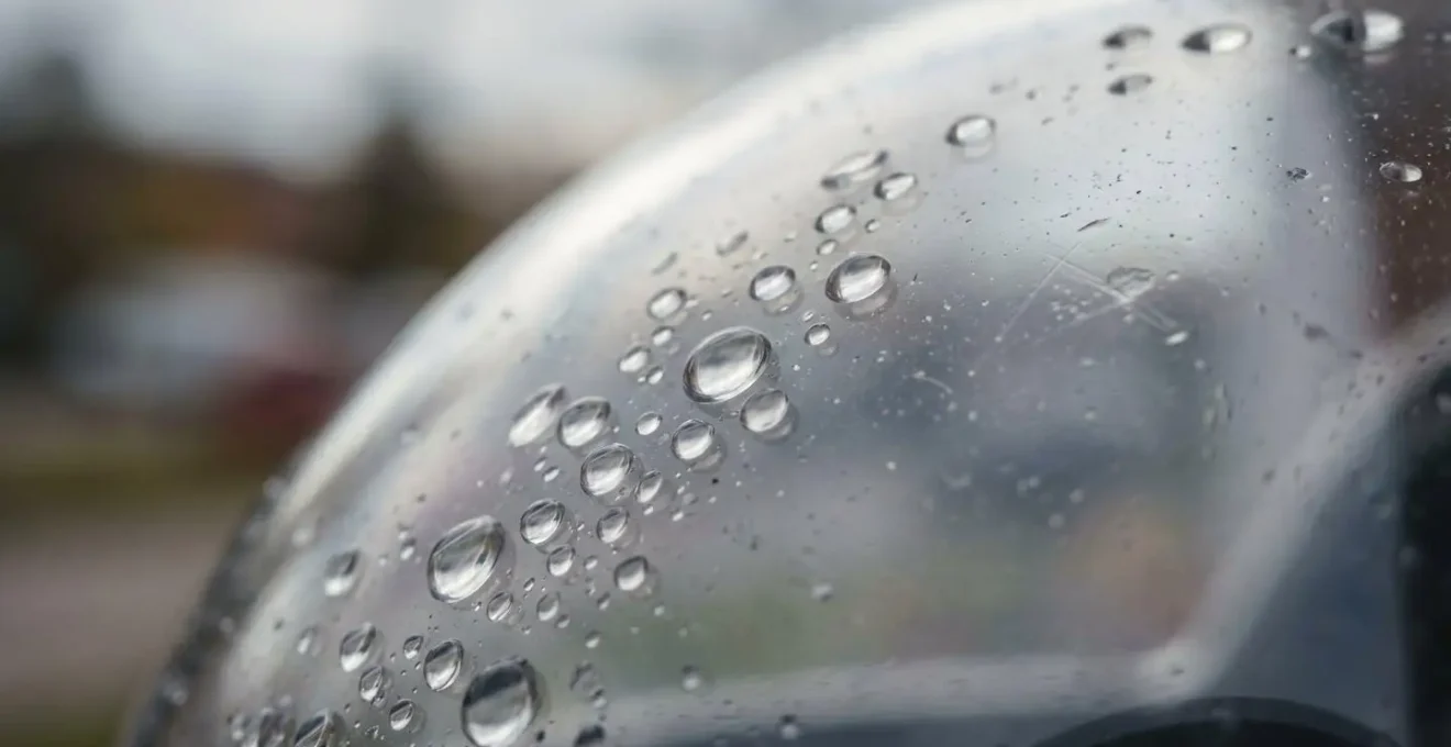 Détail macro d'un dôme de caméra de surveillance extérieure avec gouttes d'eau et texture translucide