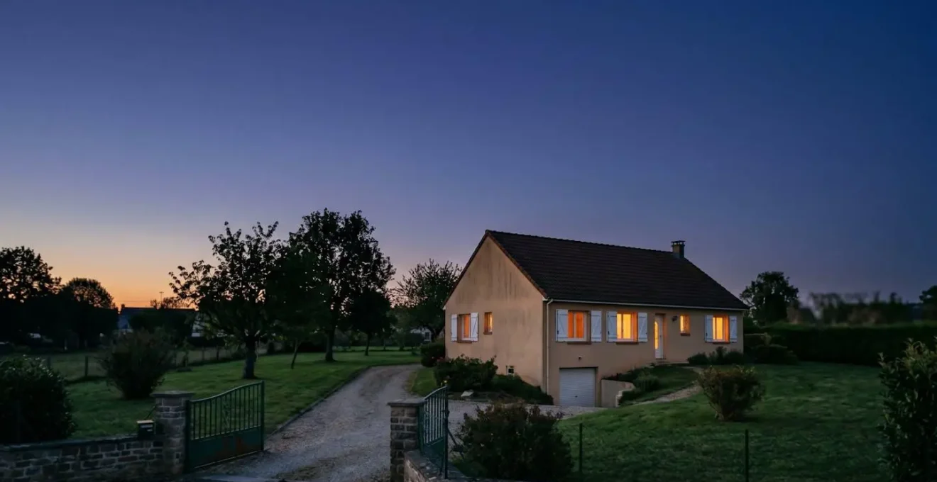 Ambiance minimaliste montrant une maison ancienne au crépuscule avec éclairage intérieur chaleureux